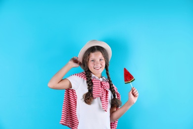 Little girl with candy on color background