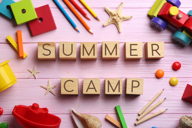 Photo of Flat lay composition with phrase SUMMER CAMP made of cubes on pink wooden background