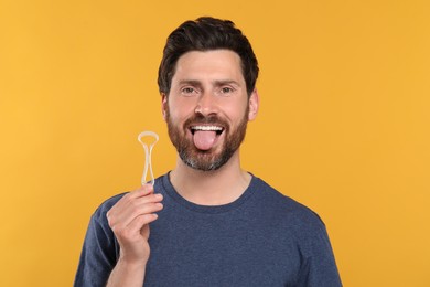 Photo of Happy man with tongue cleaner on yellow background