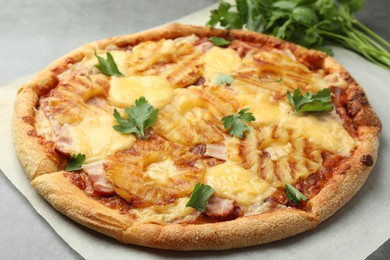 Photo of Delicious pineapple pizza with parsley on gray table, closeup
