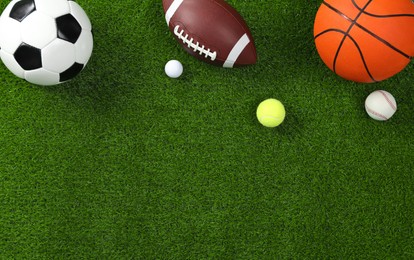 Photo of Many different sports balls on green grass, flat lay. Space for text