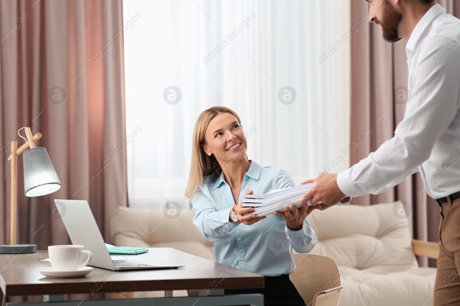 Photo of Man giving documents to happy colleague in office