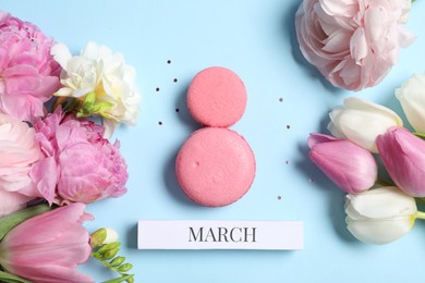 Photo of International Women's day. 8th of March made with delicious macarons and beautiful flowers on light blue background, flat lay