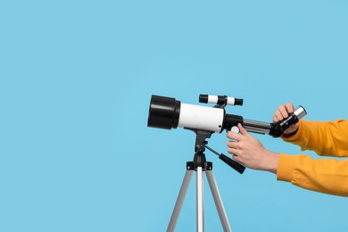 Photo of Astronomer setting up telescope on light blue background, closeup. Space for text