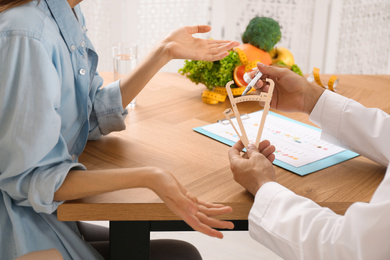 Photo of Nutritionist consulting patient at table in clinic, closeup