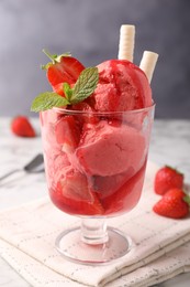 Tasty strawberry ice cream with fresh berries and wafer rolls in glass dessert bowl on table, closeup