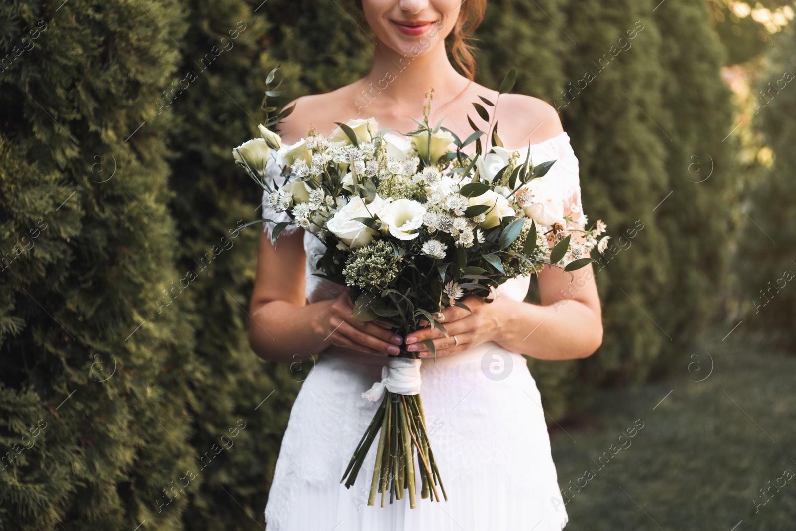 Photo of Bride in beautiful wedding dress with bouquet outdoors, closeup