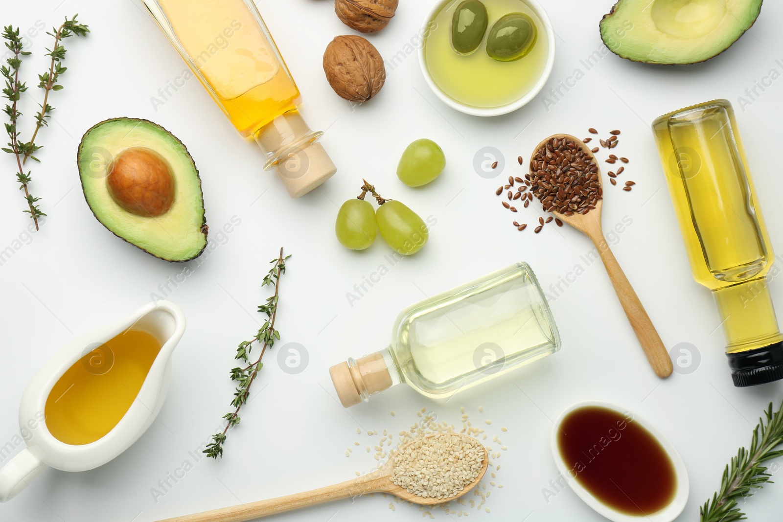 Photo of Vegetable fats. Different oils in glass bottles and ingredients on white table, flat lay