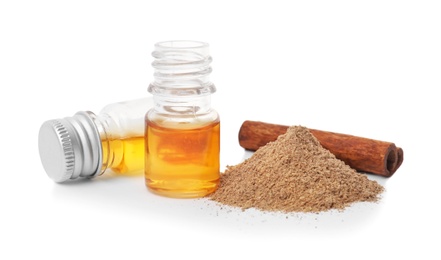 Photo of Bottles of cinnamon oil, powder and stick on white background