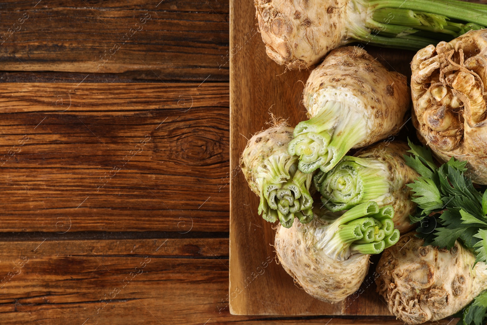 Photo of Fresh raw celery roots on wooden table, top view. Space for text
