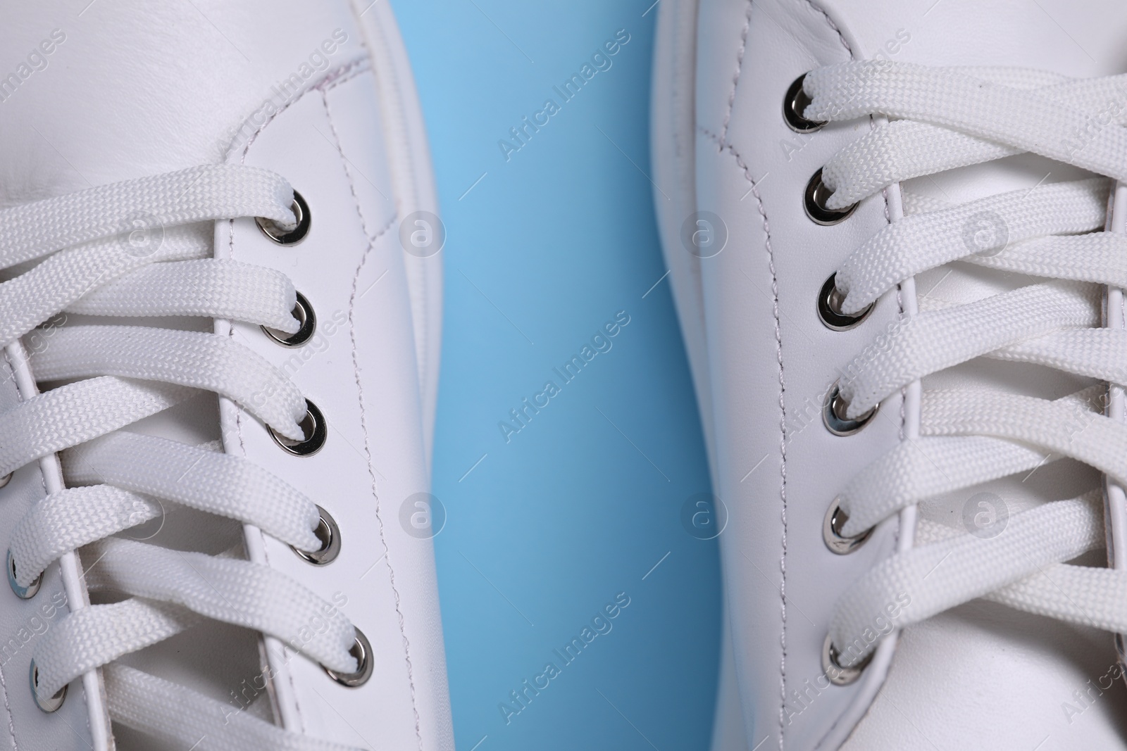 Photo of Pair of stylish white sneakers on light blue background, top view