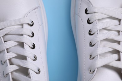 Photo of Pair of stylish white sneakers on light blue background, top view