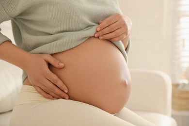 Pregnant woman at home, closeup. Choosing baby name
