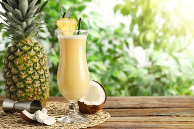 Tasty Pina Colada cocktail and ingredients on wooden table, space for text