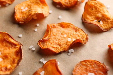 Photo of Sweet potato chips with salt on color background, closeup