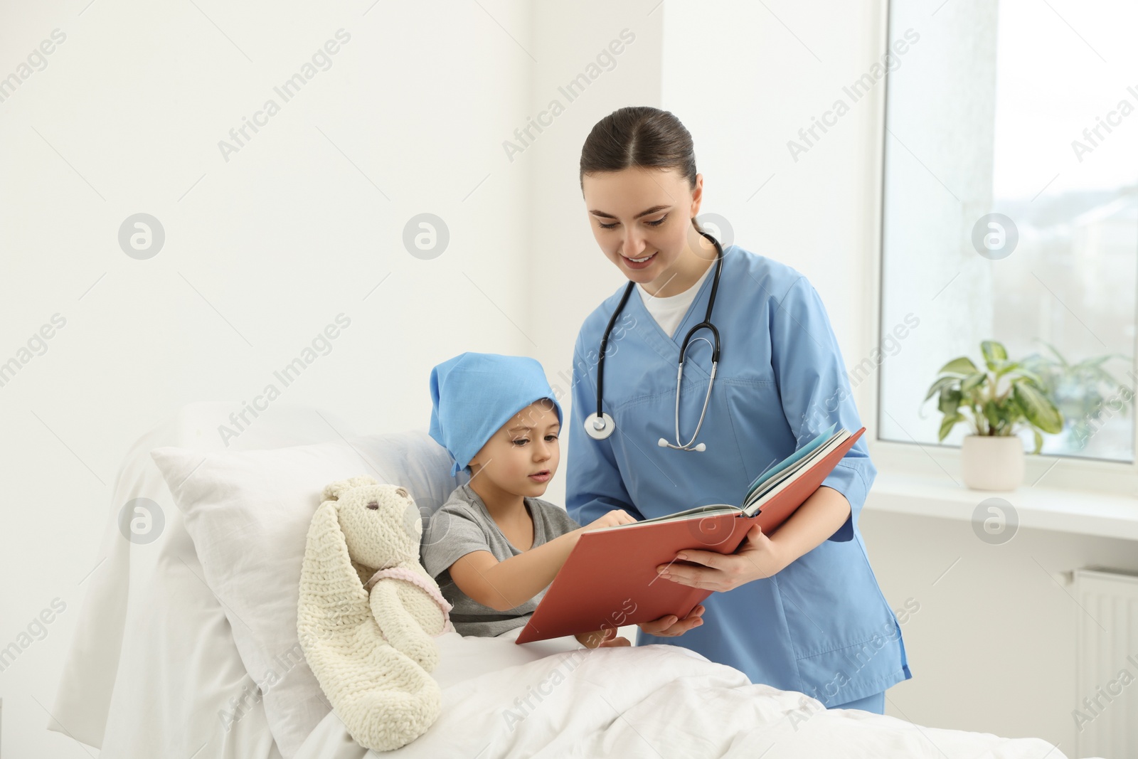 Photo of Childhood cancer. Doctor and patient reading book in hospital