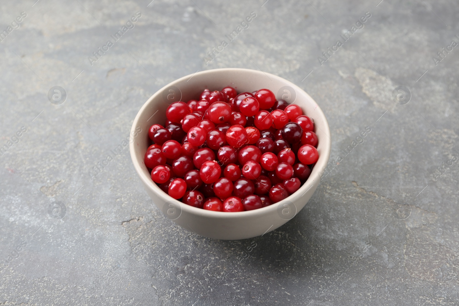 Photo of Fresh ripe cranberries in bowl on grey table