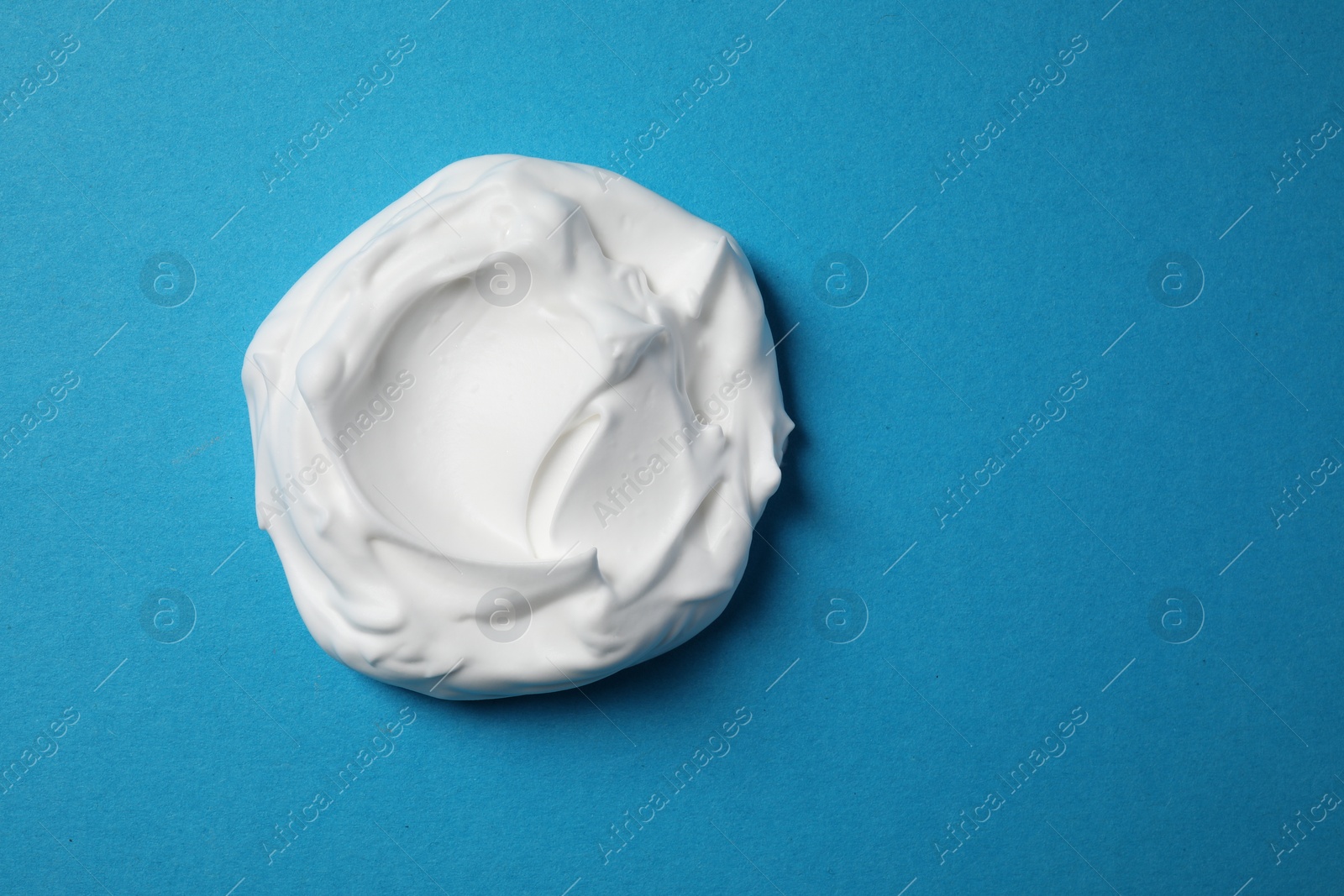 Photo of Sample of shaving foam on blue background, top view. Space for text