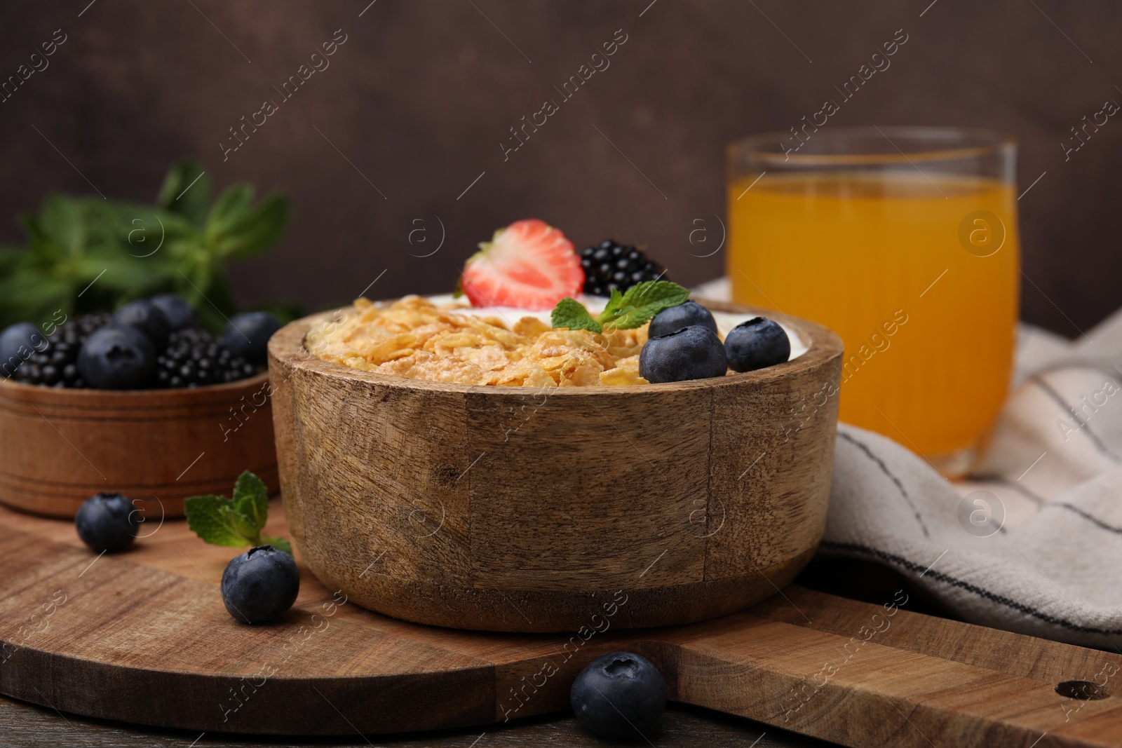 Photo of Delicious crispy cornflakes, yogurt and fresh berries in bowl on table. Healthy breakfast