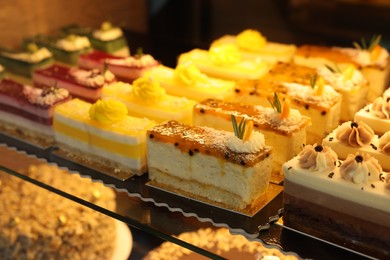 Photo of Different delicious cakes on counter in bakery shop, closeup