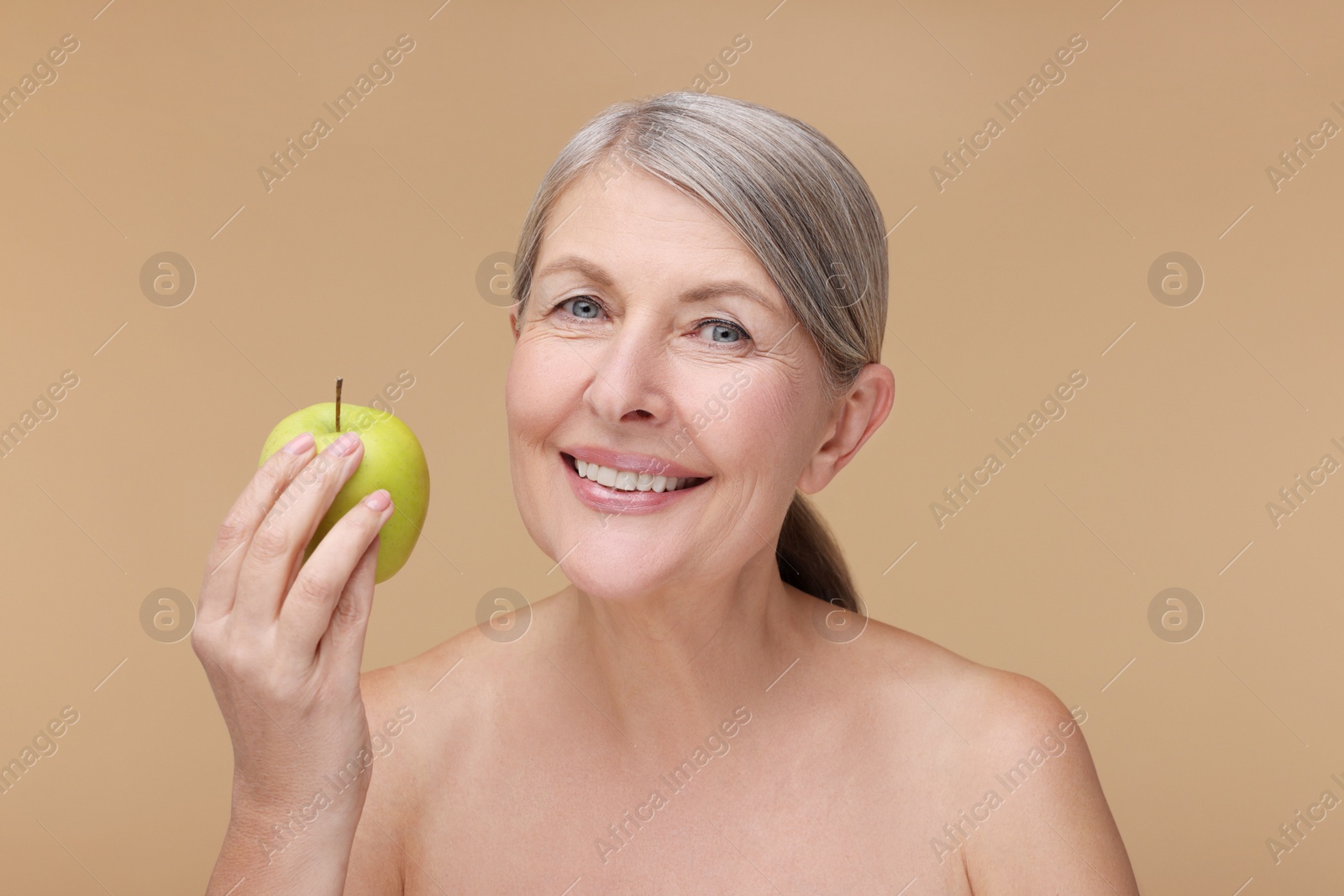 Photo of Beautiful woman with fresh apple on beige background. Vitamin rich food