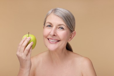 Photo of Beautiful woman with fresh apple on beige background. Vitamin rich food