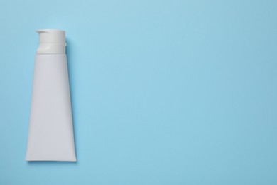 Photo of Blank tube of toothpaste on light blue background, top view. Space for text