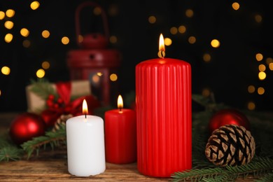 Burning candles and Christmas decor on wooden table against blurred festive lights