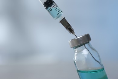 Photo of Filling syringe with medicine from vial on blurred background, closeup. Space for text