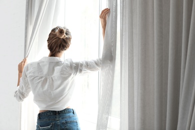 Photo of Young happy woman near window at home. Lazy morning