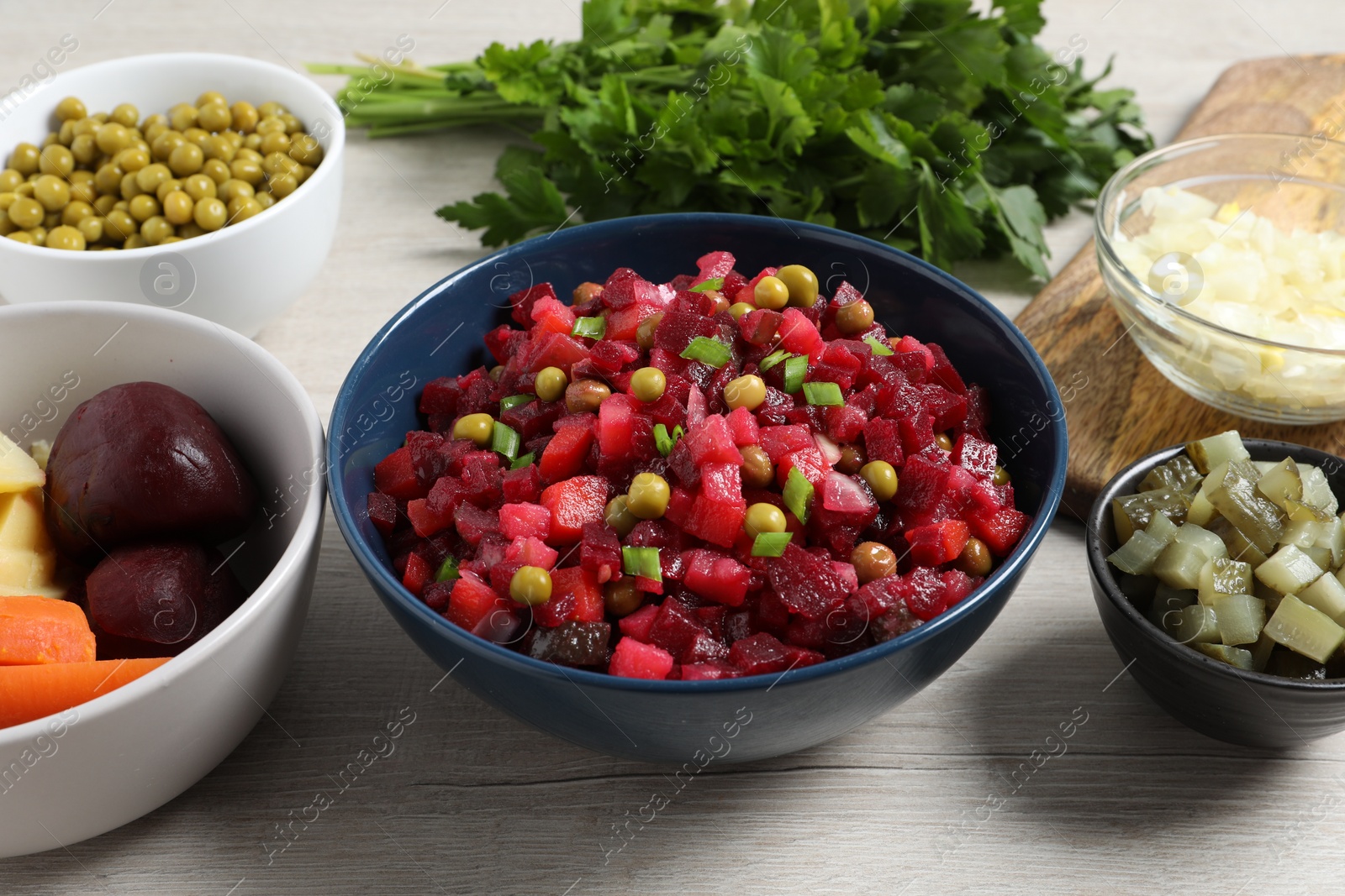 Photo of Bowl of delicious fresh vinaigrette salad and ingredients on wooden table