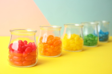 Photo of Jars of colorful jelly beans on table