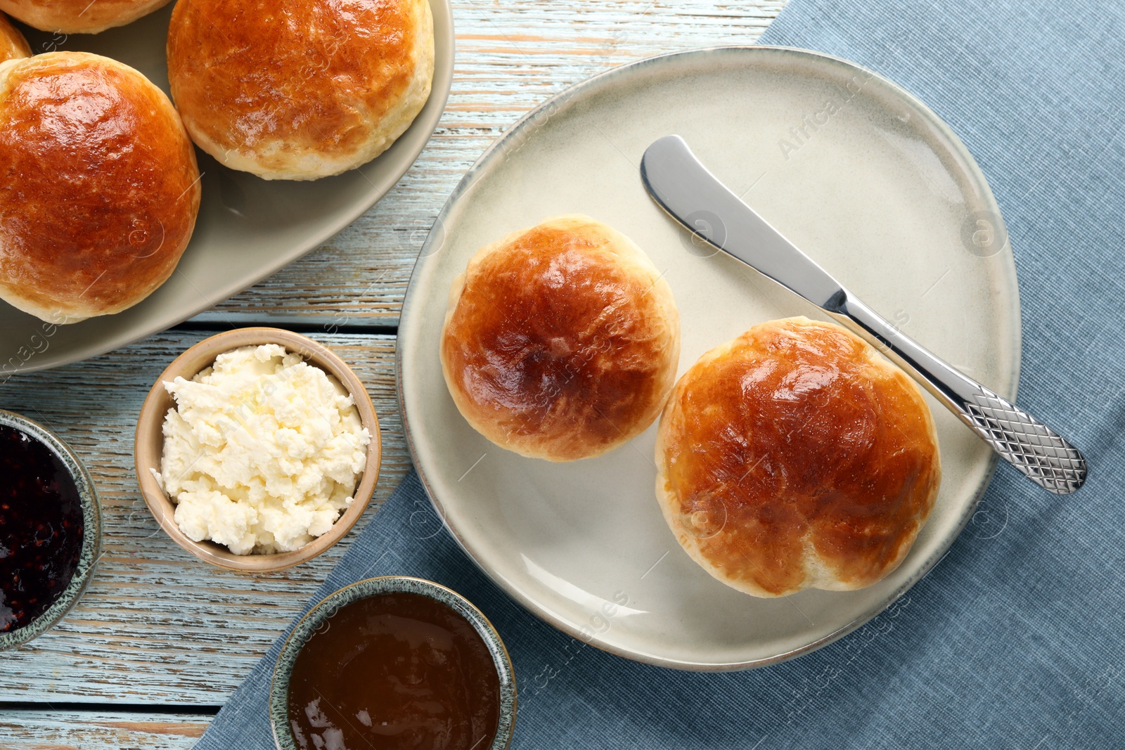 Photo of Tasty scones prepared on soda water, chocolate paste, jam and cottage cheese on wooden table, flat lay