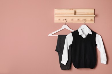 Photo of School uniform hanging on beige wall. Space for text