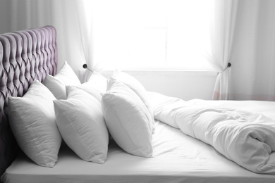 Photo of Modern bed with soft pillows near window