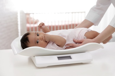 Doctor weighting African-American baby on scales in light room