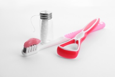 Photo of New tongue cleaner, dental floss and toothbrush with paste on white background