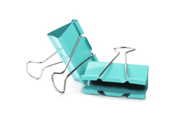 Photo of Turquoise binder clips on white background. Stationery