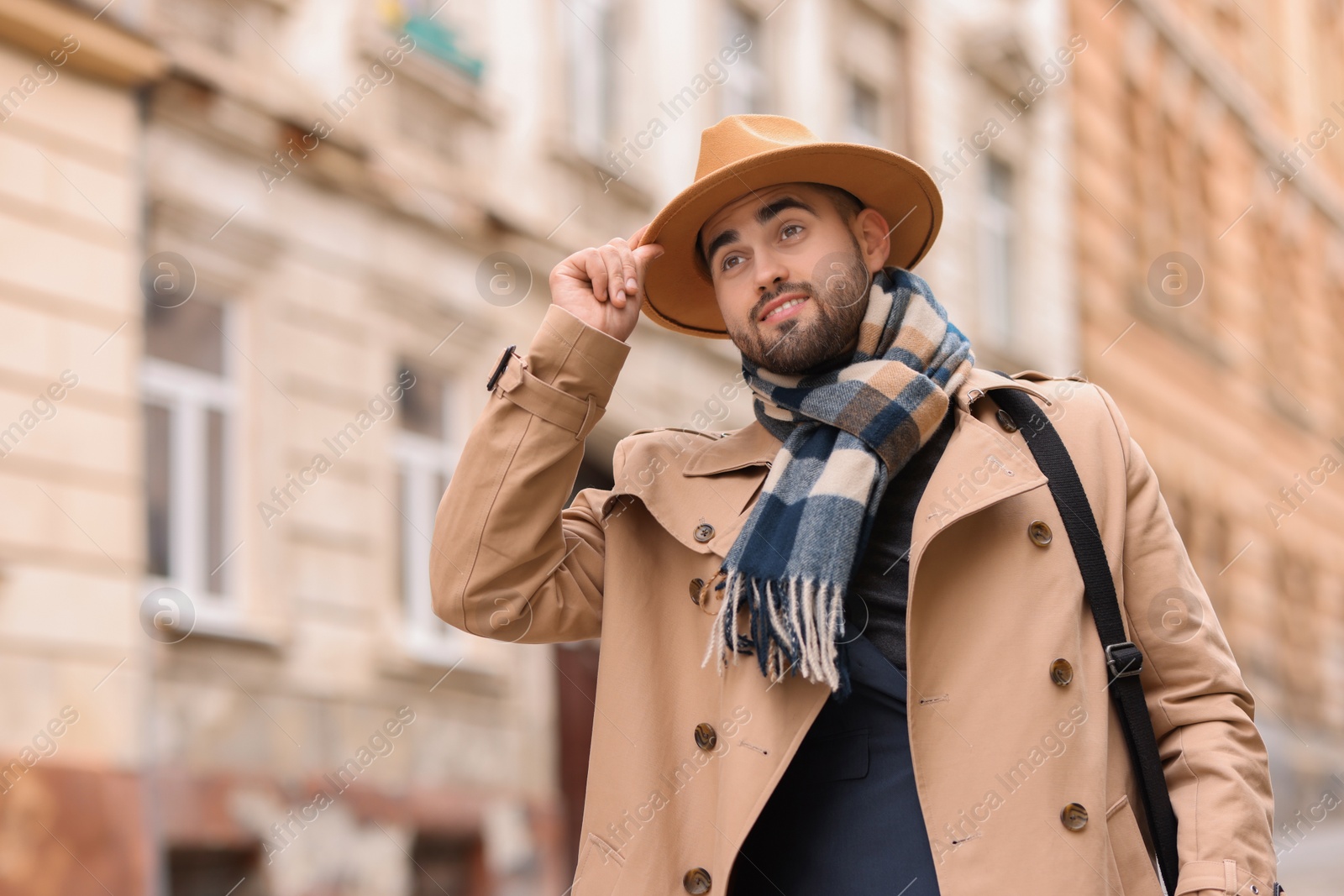 Photo of Smiling man in warm scarf on city street. Space for text