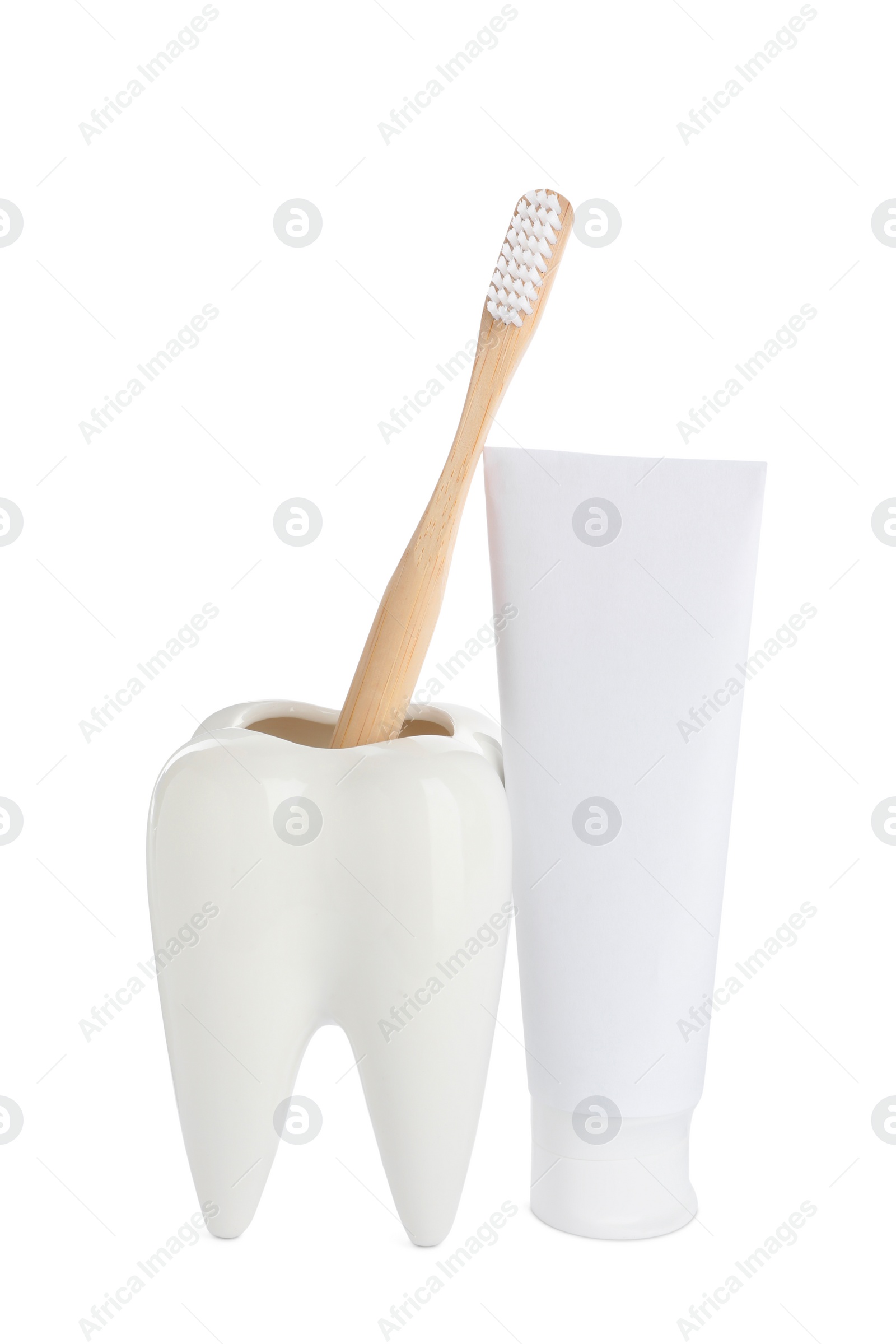 Photo of Tooth shaped holder with brush near tube of toothpaste on white background