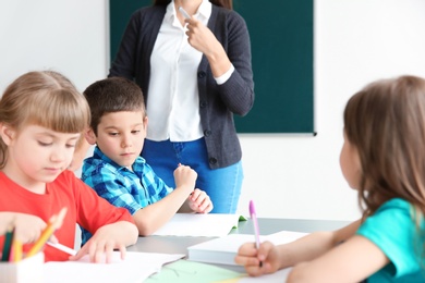 Female teacher helping boy with his task in classroom at school