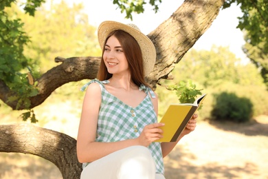 Photo of Young woman reading book on tree in park