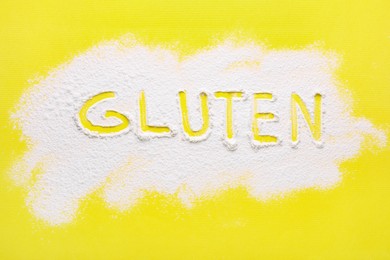 Photo of Word Gluten written with flour on yellow background, top view