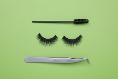 Photo of Flat lay composition with fake eyelashes, brush and tweezers on green background