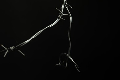 Photo of Metal barbed wire on black background, closeup