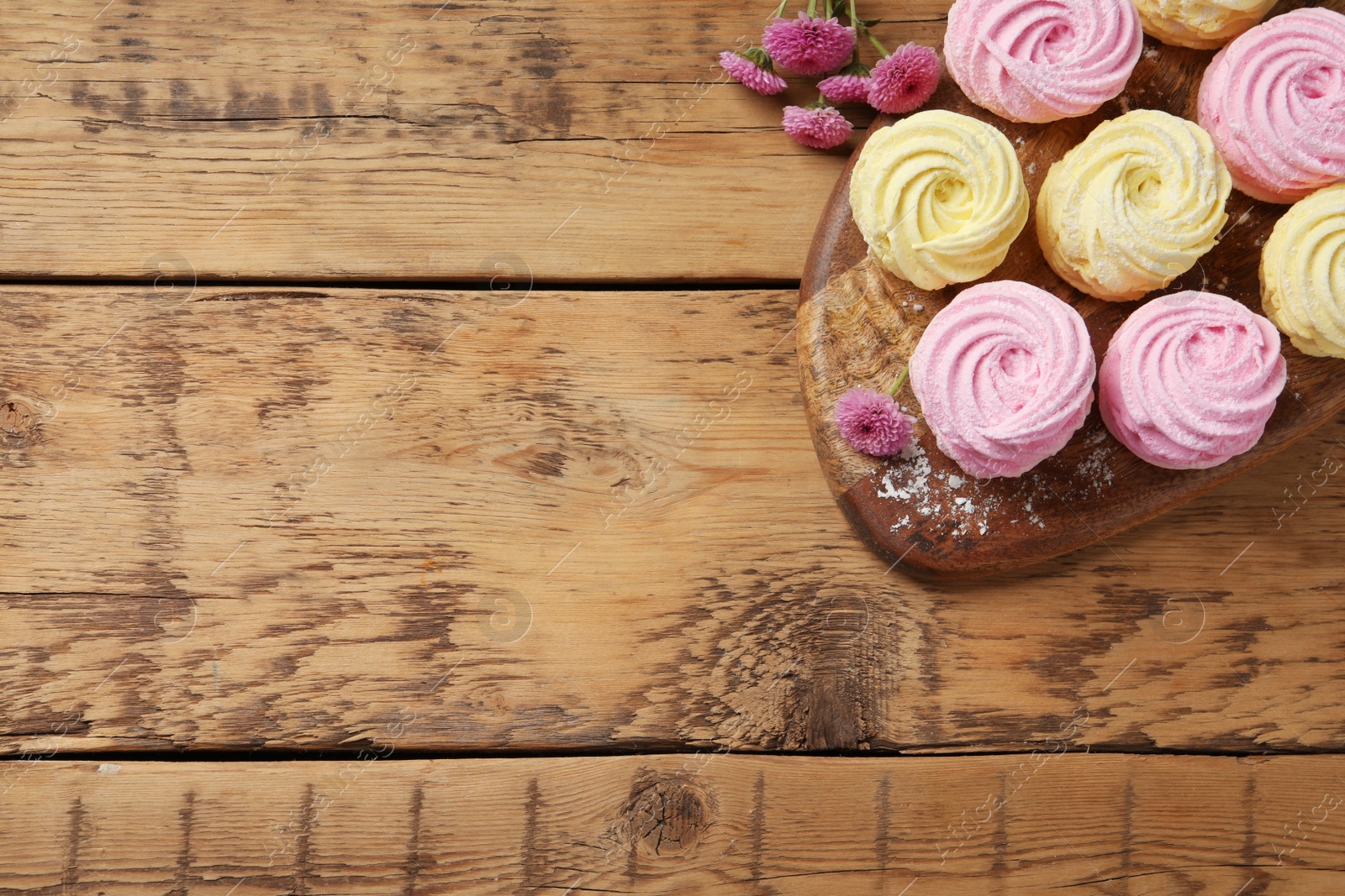 Photo of Delicious pink and yellow marshmallows on wooden table, top view. Space for text