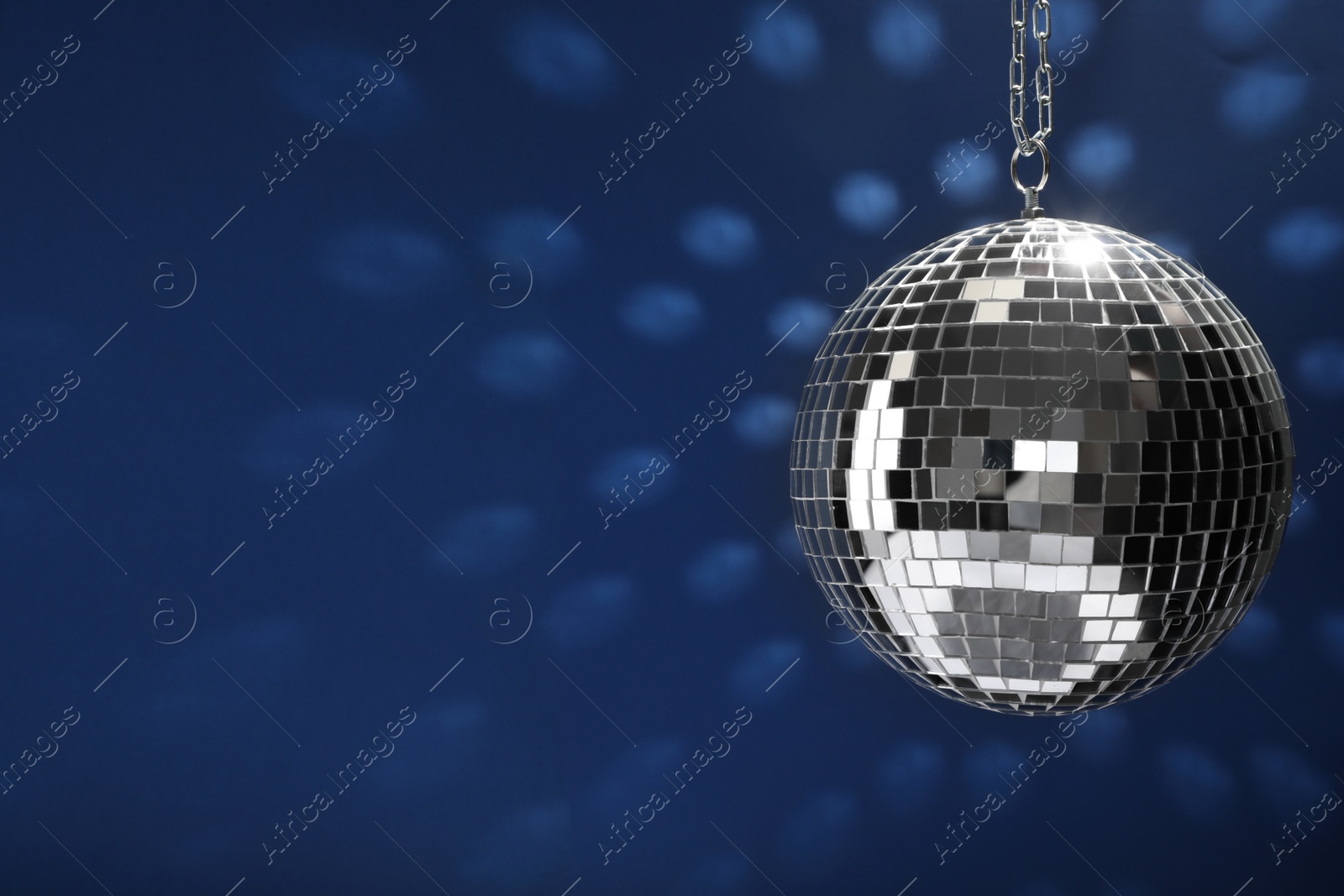 Photo of Shiny disco ball on blue background, space for text