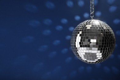 Shiny disco ball on blue background, space for text