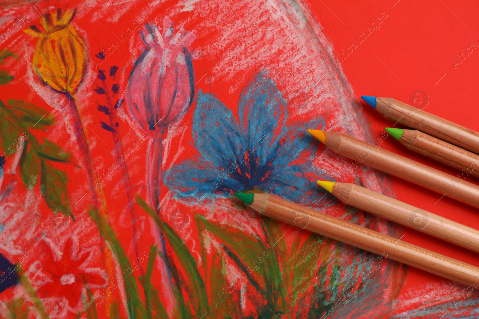 Photo of Colorful pastel pencils on beautiful painting, flat lay
