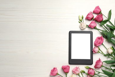 Photo of E-book reader with flowers on white wooden table, flat lay. Space for text